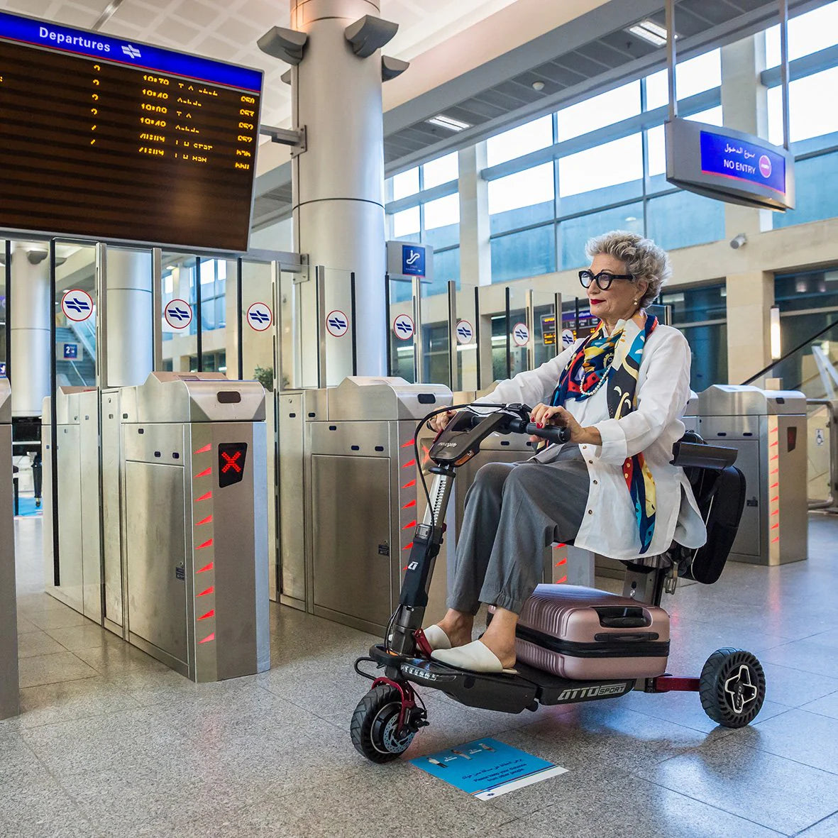 a lady at an airport in the UK with her mobility scooter and suitcase ready to fold up and go