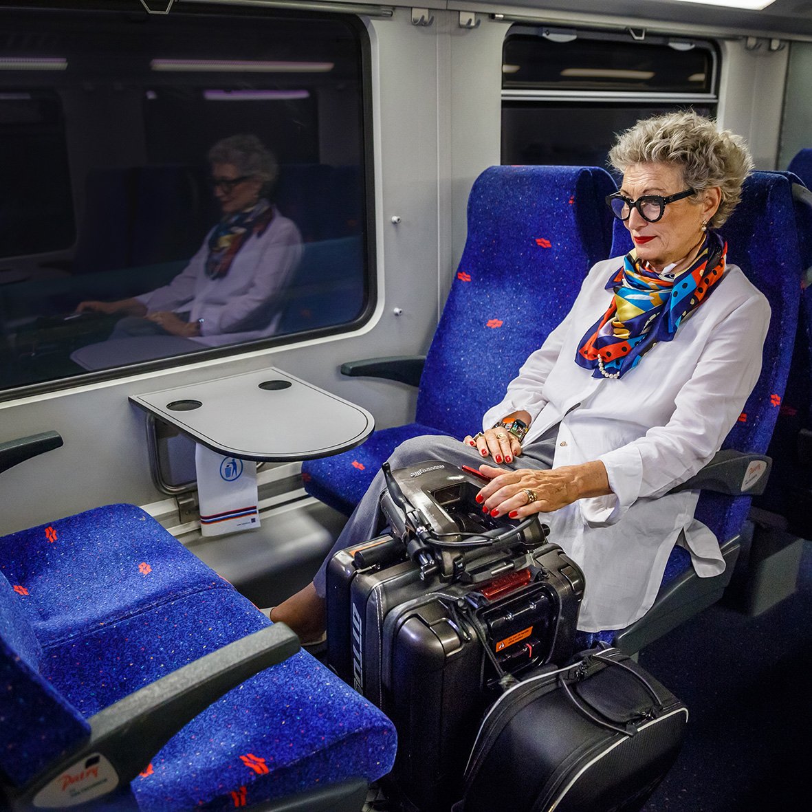 A lady travelling on a train with her mobility scooter folded up alongside her - ATTO Sport United Kingdom UK