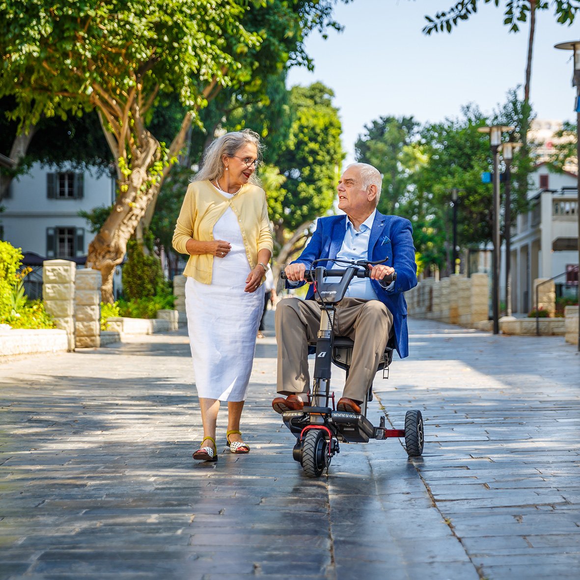 A lady walking alongside a man on an ATTO Sport mobility scooter